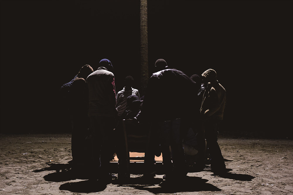 They play a game under the streetlight in Calais, France on Aug. 11, 2015.